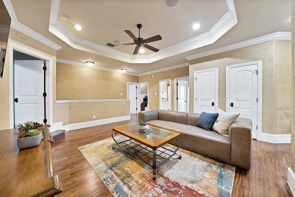 hand scraped hardwood floors throughout, tray ceiling with recessed lighting and a ceiling fan, and multiple white panel doors with dark hardware