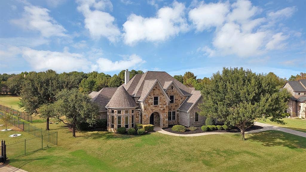 Stone and brick exterior with a turret, multi-gabled roof, and extensive landscaping