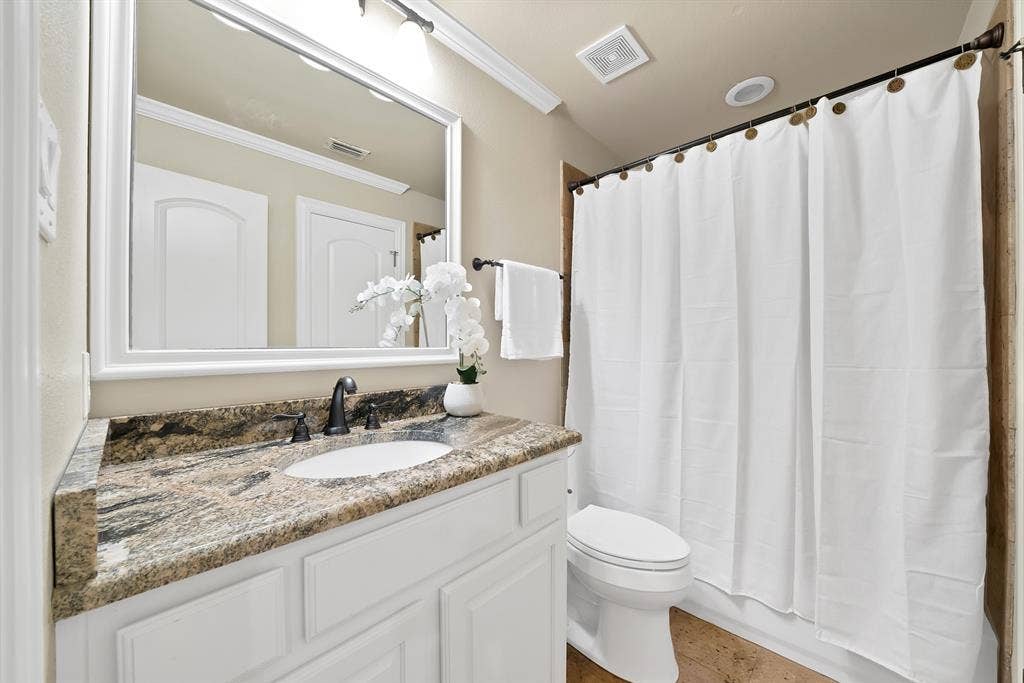 Vanity with a granite countertop, undermount sink, and dark bronze faucet