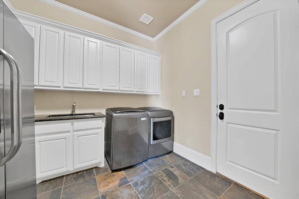 White shaker cabinetry, black countertop with undermount sink, multi-toned tile flooring, and a white paneled door with an arched top