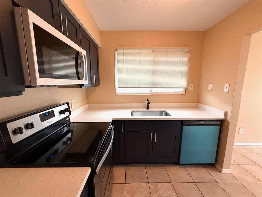 2705 Tanglewood Drive, Lancaster, TX 75134 Kitchen featuring dark wood-finish cabinetry, light-toned countertops, tile flooring, and stainless steel appliances