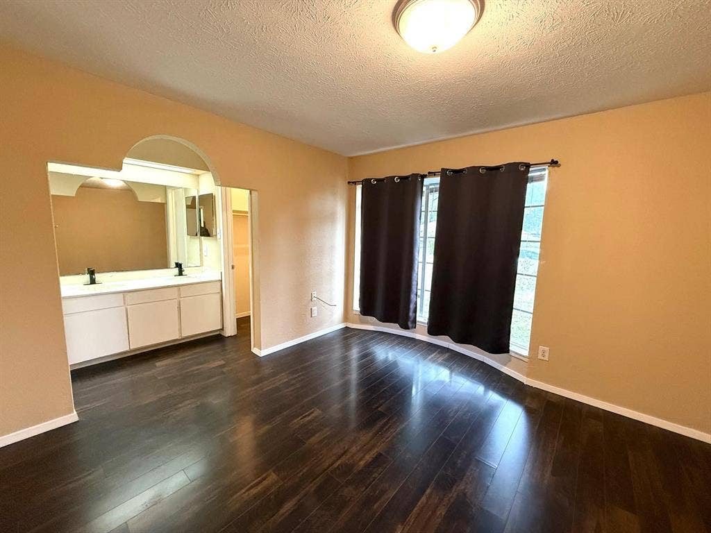 2705 Tanglewood Drive, Lancaster, TX 75134 Wood-finish flooring throughout, featuring a curved bay window, and an arched entry to a double vanity with two mirrors