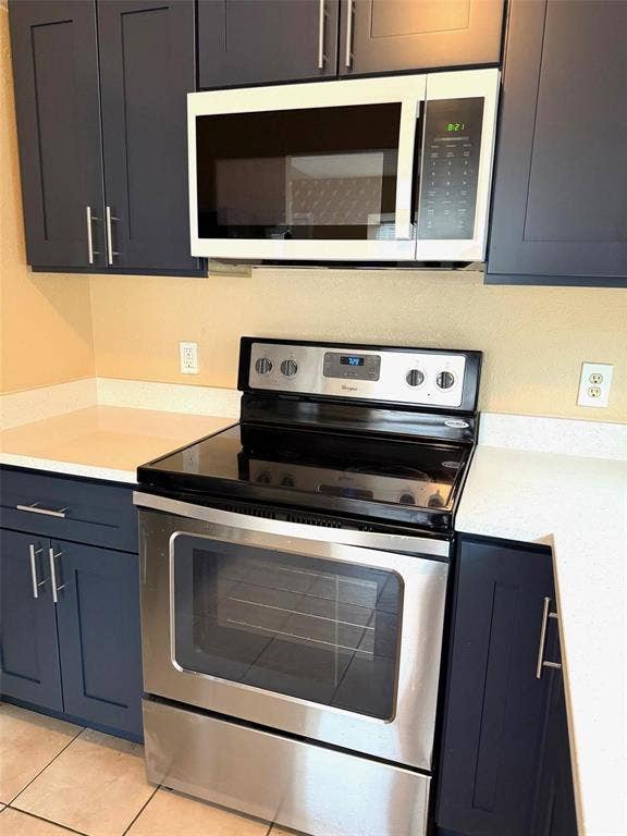 2705 Tanglewood Drive, Lancaster, TX 75134 Stainless steel electric range with a smooth cooktop, stainless steel microwave, dark cabinetry with bar pull hardware, and light-toned countertops
