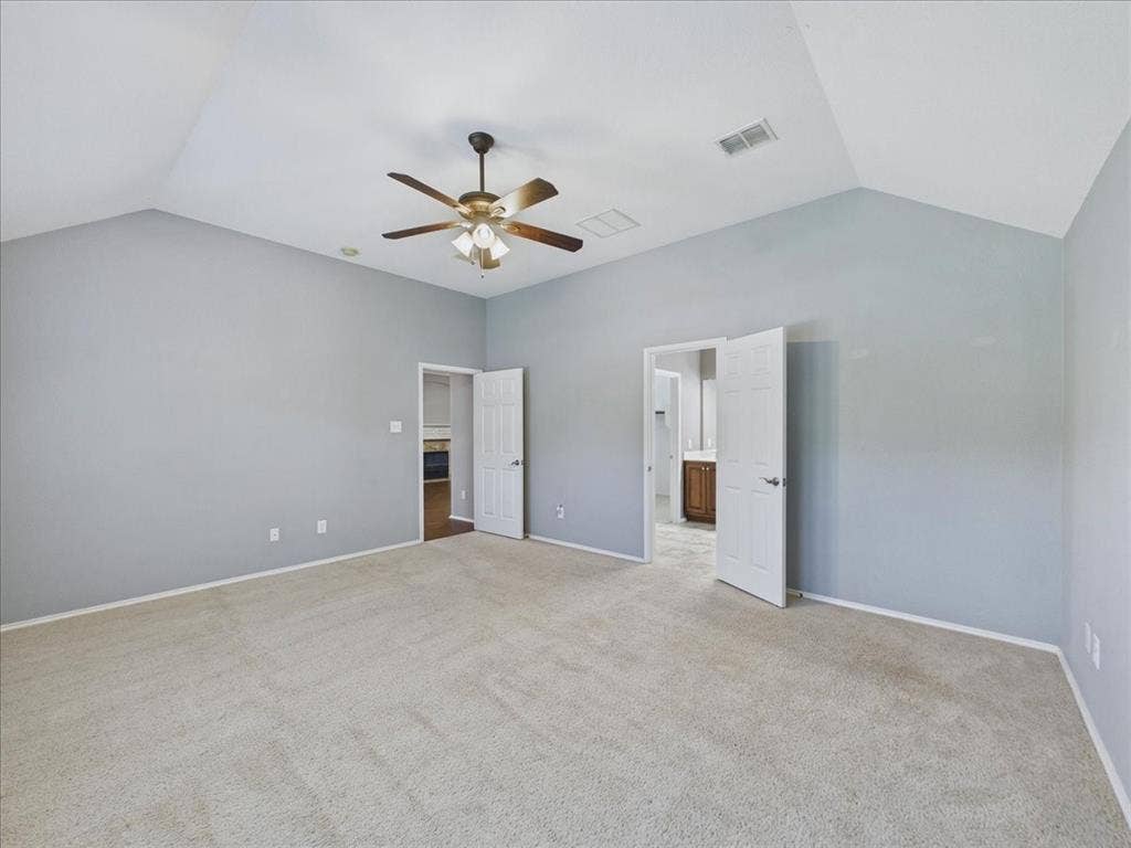 Vaulted ceiling, ceiling fan, neutral carpet, light gray wall color, and white trim