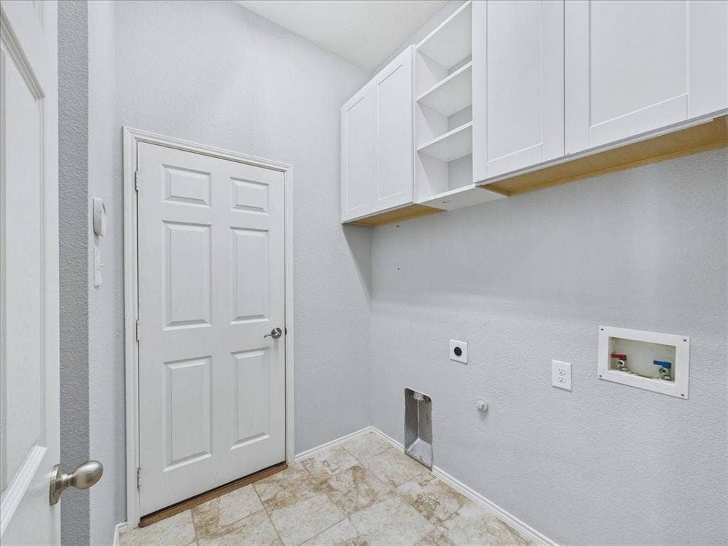 White shaker-style cabinetry with open shelving, tile flooring, and utility hookups