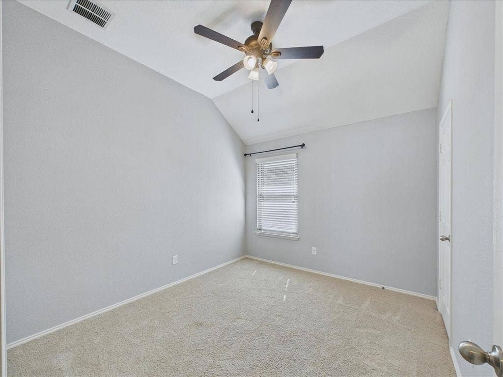 Vaulted ceiling with ceiling fan, carpeting, window with blinds, and white door
