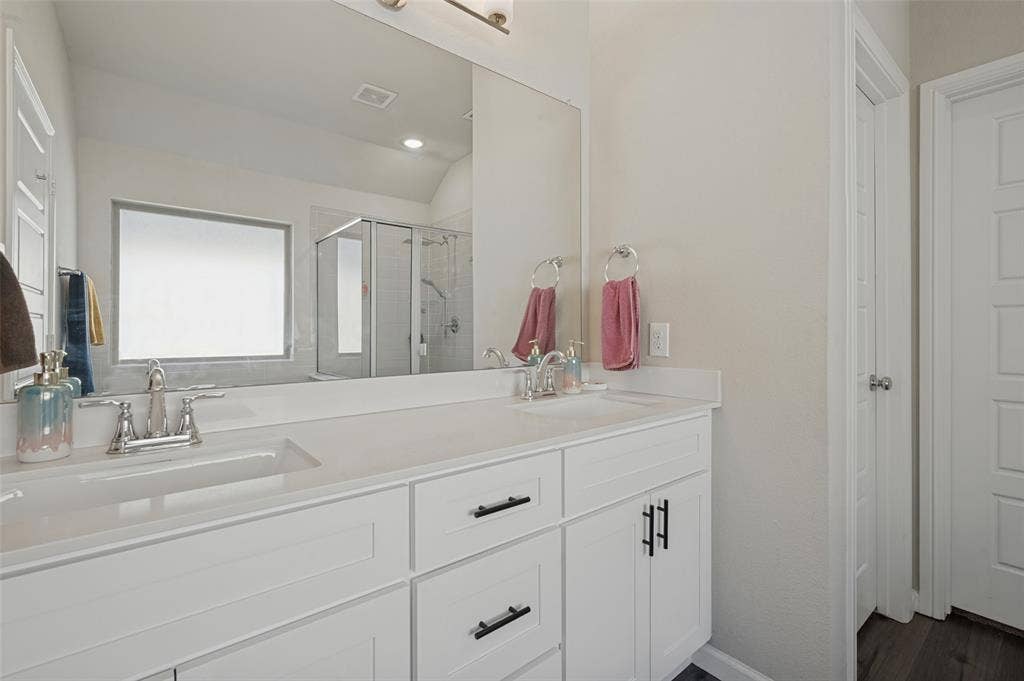 632 Cherry Hills Road, Red Oak, TX 75154 Dual vanity with white cabinetry and dark hardware, integrated sinks, chrome fixtures, and a large wall-mounted mirror