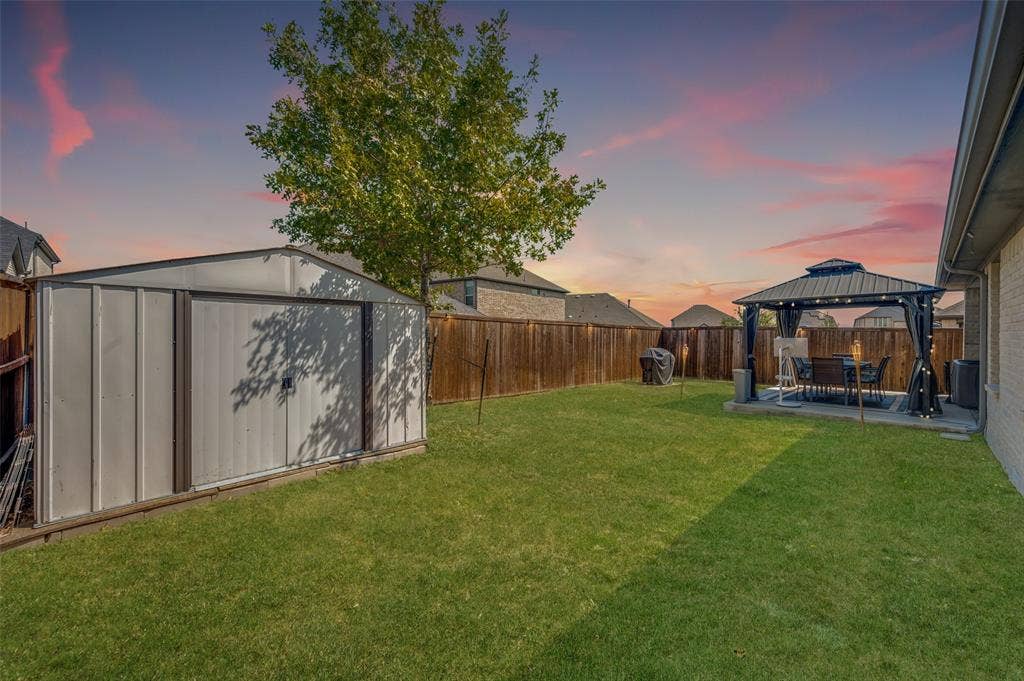 632 Cherry Hills Road, Red Oak, TX 75154 Expansive backyard with a metal storage shed, wood fence, and a patio area featuring a gazebo