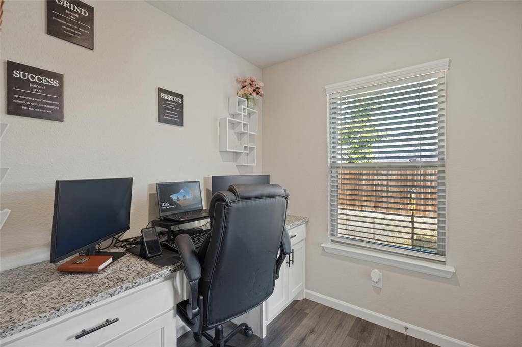 632 Cherry Hills Road, Red Oak, TX 75154 Dedicated home office featuring a wood-finish desk with quartz countertop, ergonomic seating, dual monitor setup capability, and abundant natural light from a large window with plantation shutters