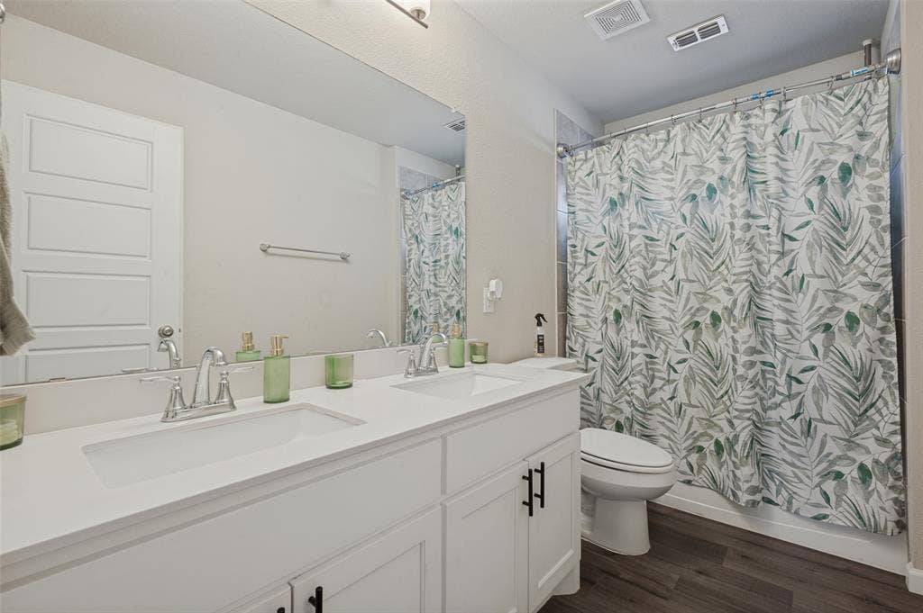 632 Cherry Hills Road, Red Oak, TX 75154 Dual vanity with integrated sinks, chrome fixtures, white cabinetry with black hardware, and a shower-tub combination