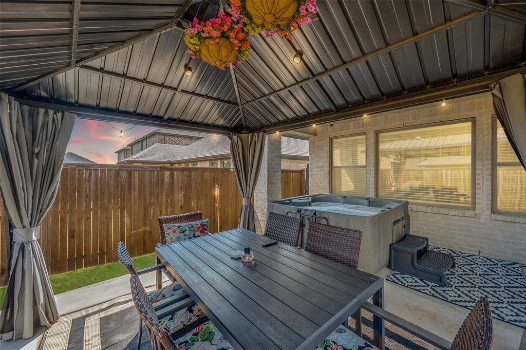 632 Cherry Hills Road, Red Oak, TX 75154 Covered patio with a metal roof and string lighting, featuring a built-in hot tub, concrete patio, and a privacy fence