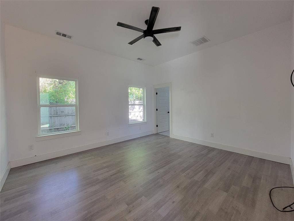 Vaulted ceilings, wood-finish flooring, and a matte black ceiling fan