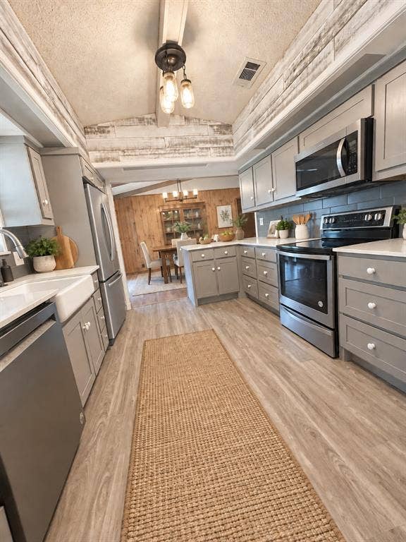 102 Rye Place, Gun Barrel City, TX 75156 Wood-finish flooring, gray cabinetry, stainless steel appliances, a white farmhouse sink, and a subway tile backsplash