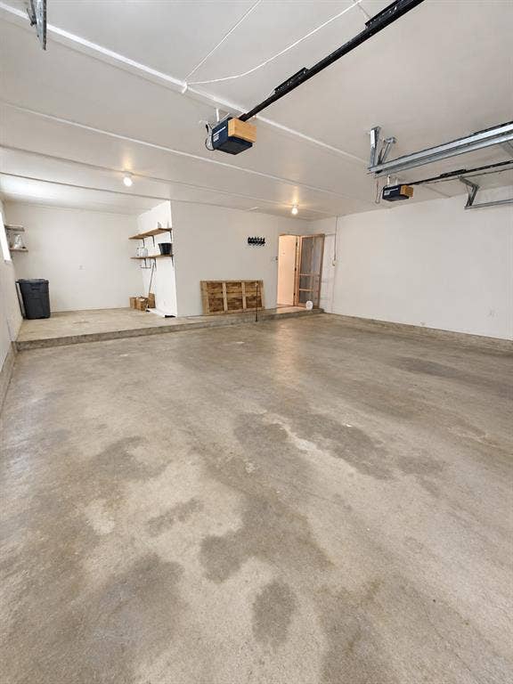 102 Rye Place, Gun Barrel City, TX 75156 Concrete flooring garage with an elevated platform, exposed ceiling beams, built-in shelving, and garage door mechanisms