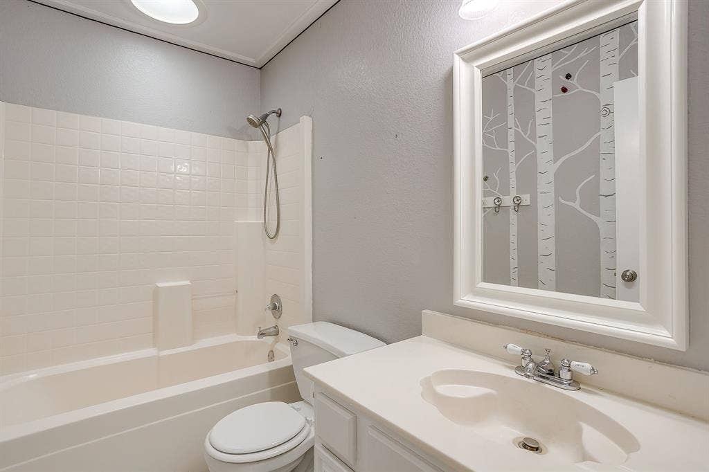 Bathroom featuring a vanity with an integrated basin, a wall-mounted framed mirror, a tub and shower combination with a handheld fixture, and recessed ceiling lighting