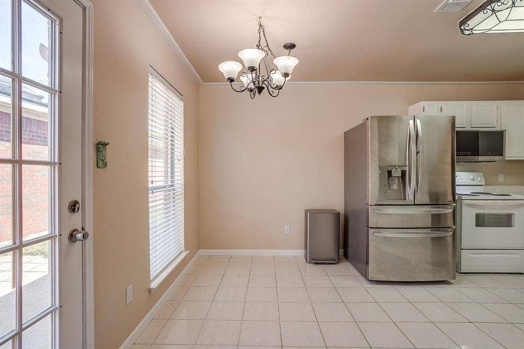 Kitchen featuring ceramic tile flooring, a multi-arm chandelier, white upper cabinetry, stainless steel French-door refrigerator, and a glass-paneled exterior door
