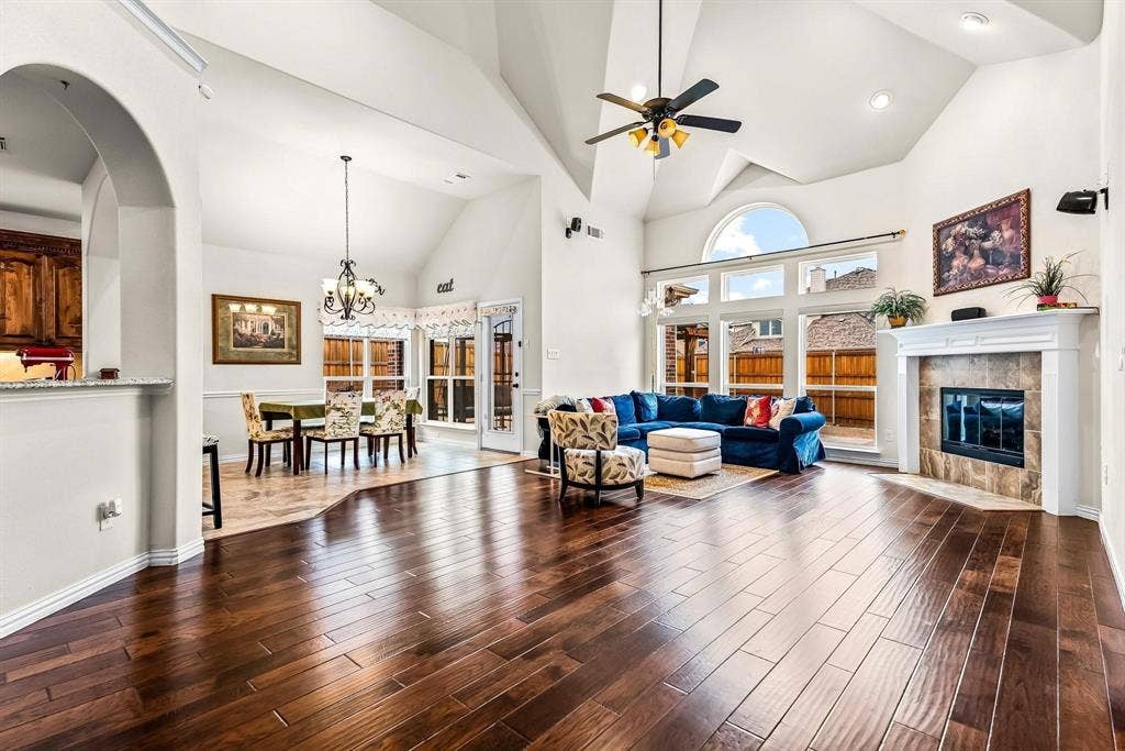 12467 Fallcreek Drive, Frisco, TX 75035 Vaulted ceilings with a ceiling fan, fireplace with a mantel, wood-finish flooring, and expansive windows