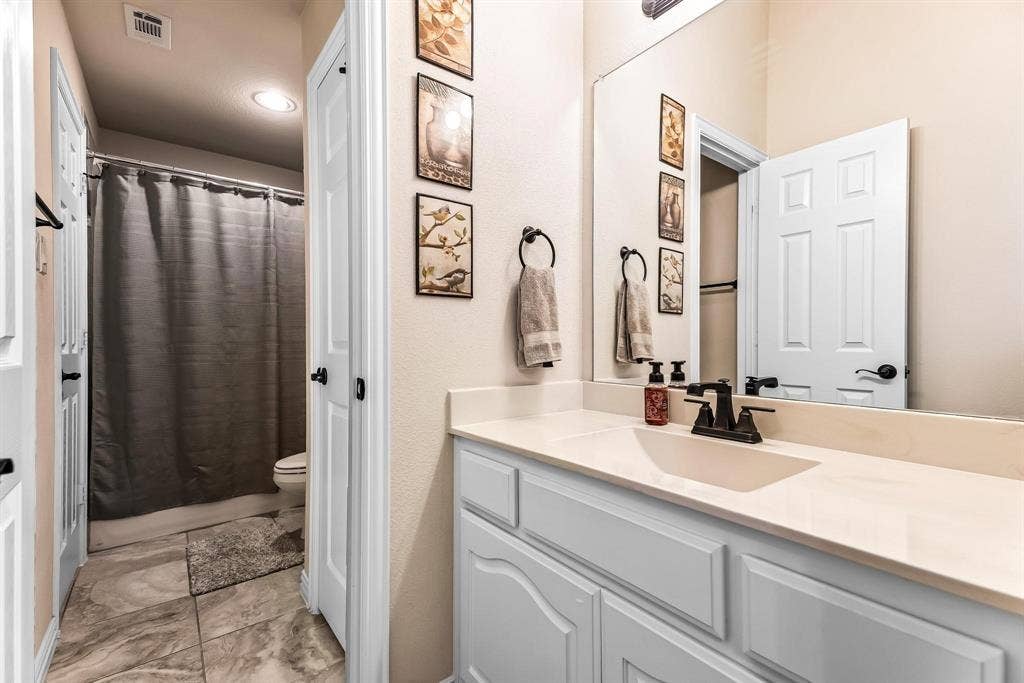12467 Fallcreek Drive, Frisco, TX 75035 Single vanity with integrated sink, white cabinetry, light-toned countertop, and matte black faucet