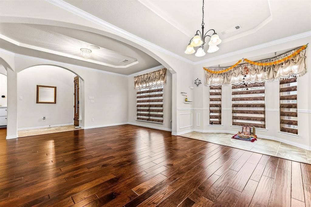 12467 Fallcreek Drive, Frisco, TX 75035 Wood-finish flooring throughout, tray ceiling with recessed lighting, arched doorway, and a chandelier lighting fixture