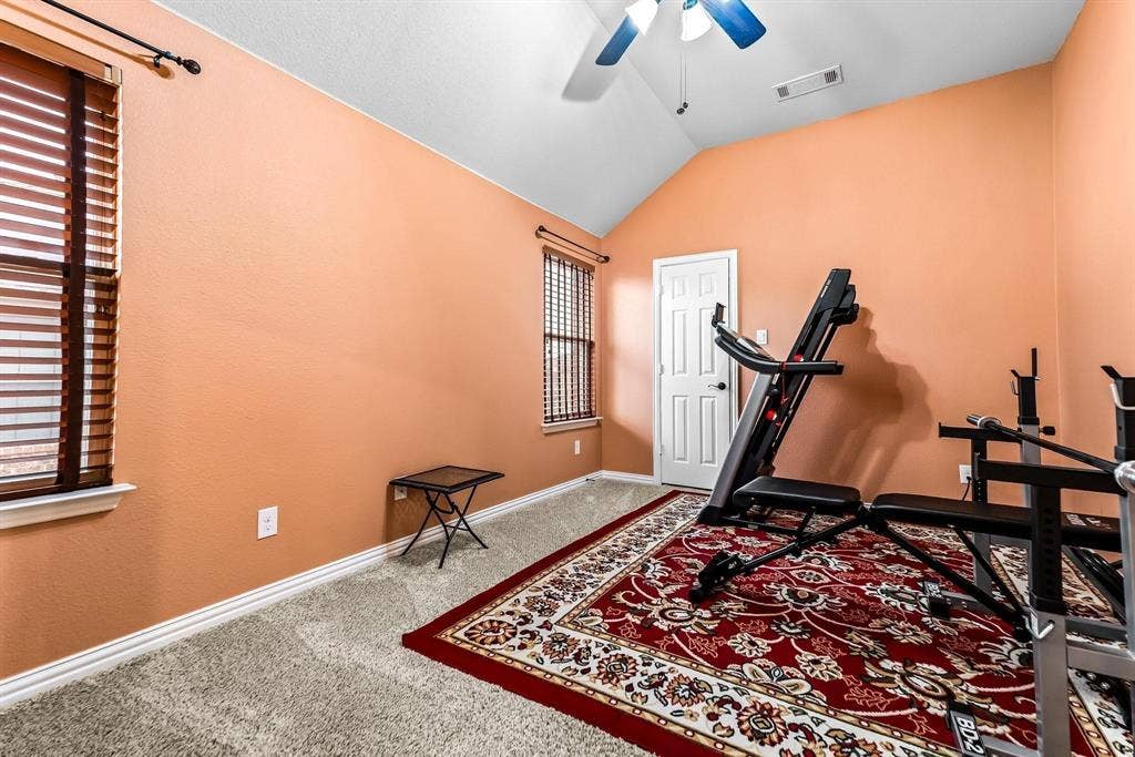 12467 Fallcreek Drive, Frisco, TX 75035 Vaulted ceiling with ceiling fan, two windows with horizontal blinds, neutral carpet, and a paneled interior door