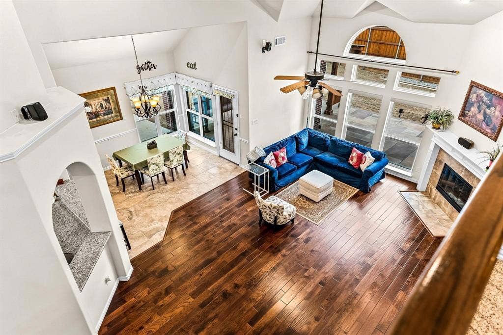 12467 Fallcreek Drive, Frisco, TX 75035 High ceilings with an arched window, wood-finish flooring, a fireplace with a stone hearth, and a dining area with tile flooring