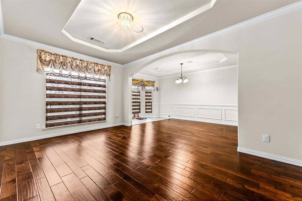 12467 Fallcreek Drive, Frisco, TX 75035 Wood-finish flooring, tray ceiling with a chandelier, crown molding, and wainscoting