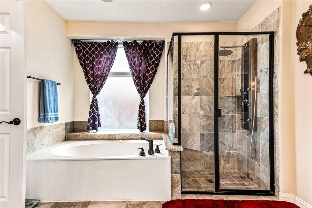 12467 Fallcreek Drive, Frisco, TX 75035 Built-in soaking tub with dark bronze fixtures, frosted window, and adjacent tiled shower with a multi-function shower panel