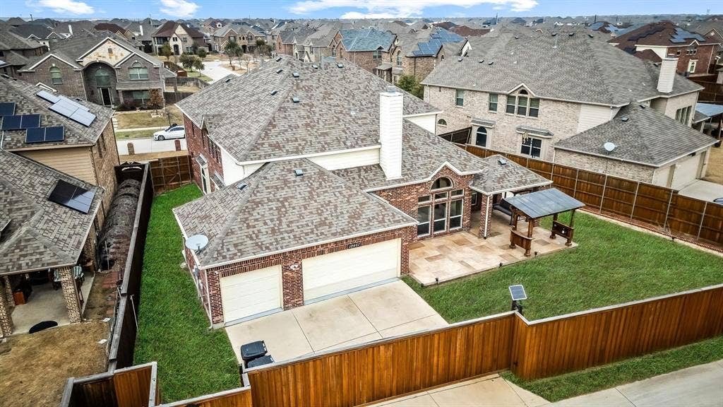 12467 Fallcreek Drive, Frisco, TX 75035 Rear elevation featuring a brick exterior, a two-car garage, an expansive patio, and a covered outdoor structure