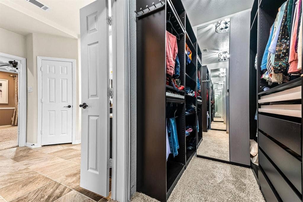 12467 Fallcreek Drive, Frisco, TX 75035 Hallway featuring tile flooring, leading to a custom closet with built-in dark wood cabinetry and carpet flooring