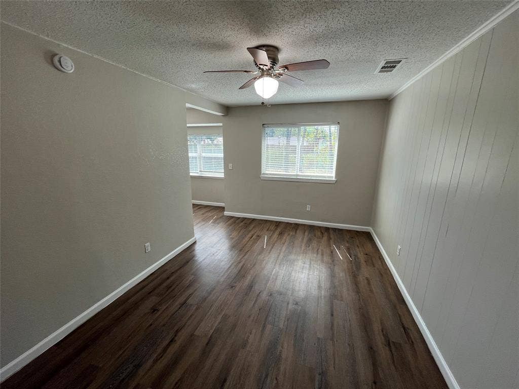 14206 Osage Drive, Balch Springs, TX 75180 Wood-finish flooring throughout, ceiling fan with integrated lighting, multiple windows with blinds, and a paneled accent wall