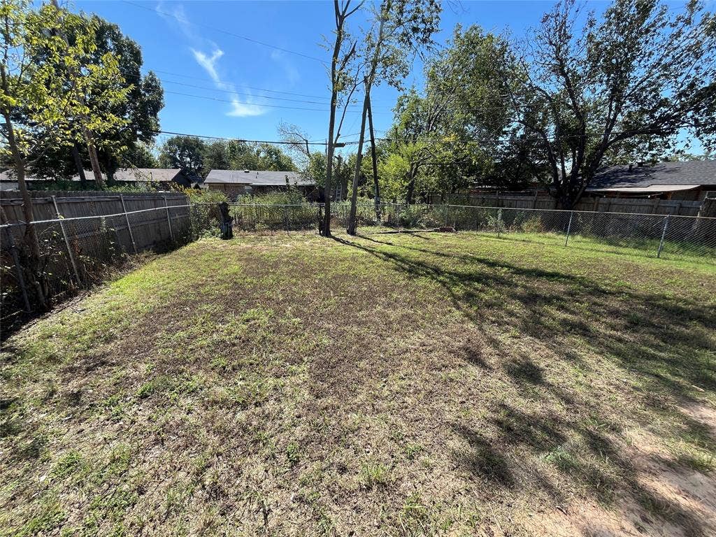 14206 Osage Drive, Balch Springs, TX 75180 Expansive outdoor space featuring a chain-link fence perimeter and mature trees