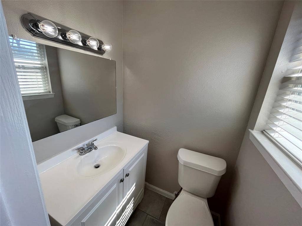 14206 Osage Drive, Balch Springs, TX 75180 White vanity with integrated sink, rectangular mirror, and chrome vanity light fixture