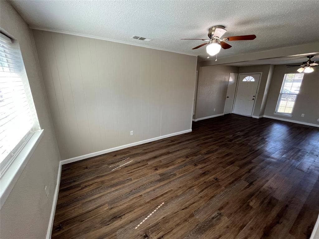 14206 Osage Drive, Balch Springs, TX 75180 Wood-finish flooring, white trim, paneled wall accent, and ceiling fans with integrated lighting