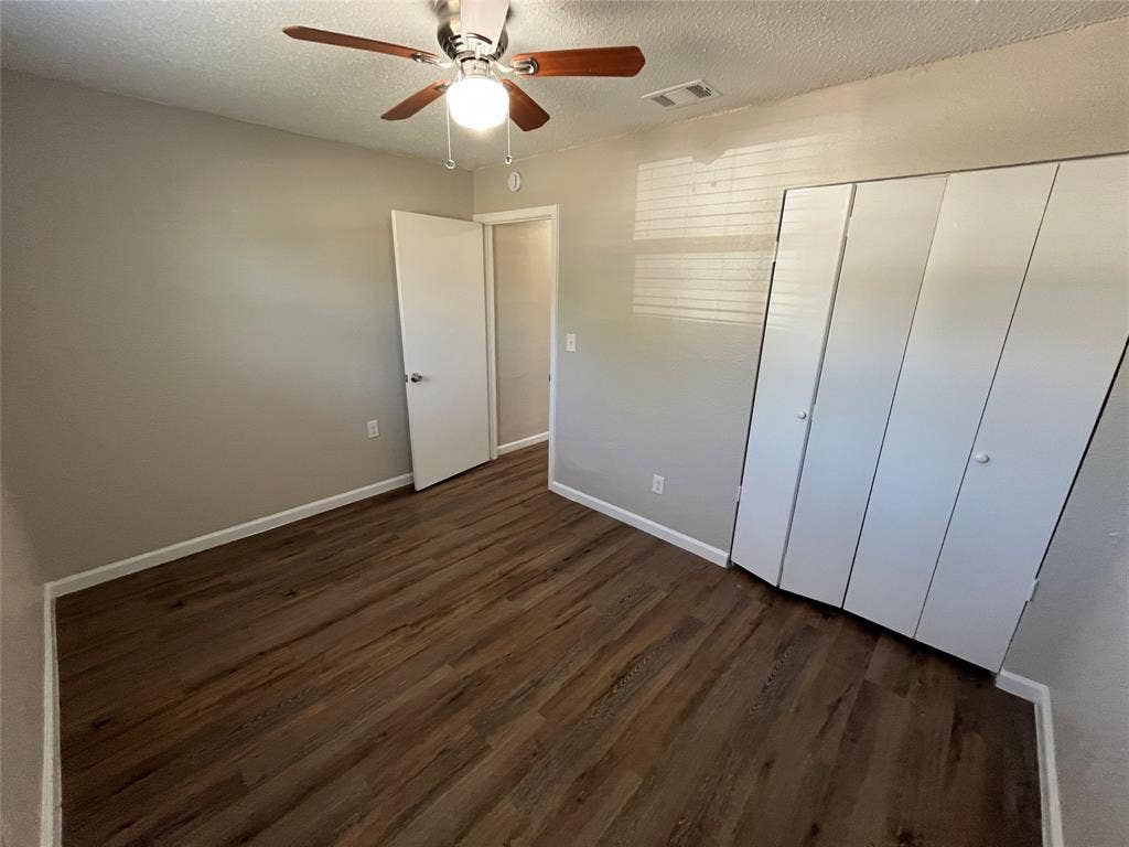 14206 Osage Drive, Balch Springs, TX 75180 Wood-finish flooring, ceiling fan with integrated lighting, bi-fold closet doors, and neutral wall paint