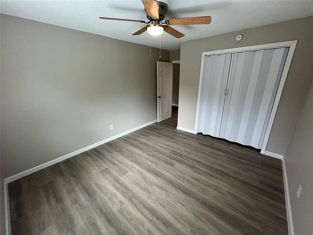 9527 Musgrave Drive, Dallas, TX 75217 Room featuring wood-finish flooring, a ceiling fan with integrated lighting, and a closet with bifold doors