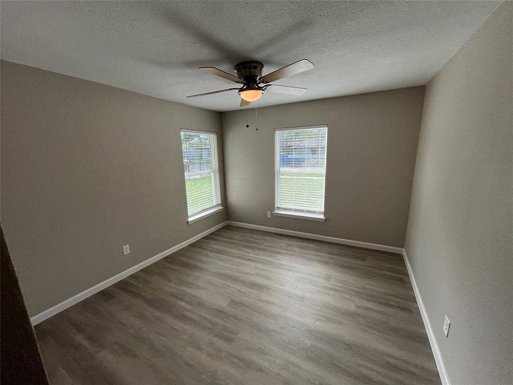 9527 Musgrave Drive, Dallas, TX 75217 Neutral-toned walls, wood-finish flooring, dual windows with blinds, and a central ceiling fan with an integrated light fixture