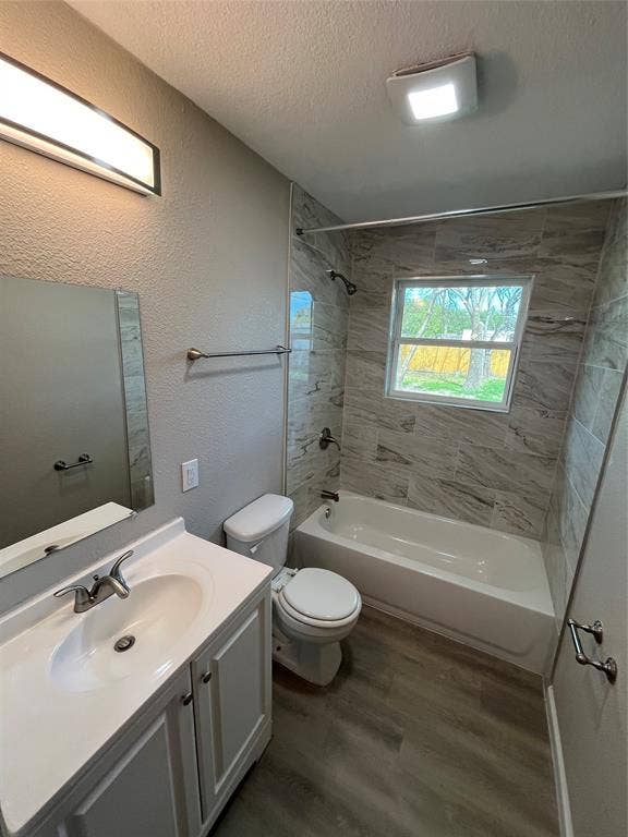 9527 Musgrave Drive, Dallas, TX 75217 Bathroom featuring a white vanity with a composite countertop, wood-finish flooring, shower-tub combination with horizontal tile surround, and a wall-mounted LED vanity light