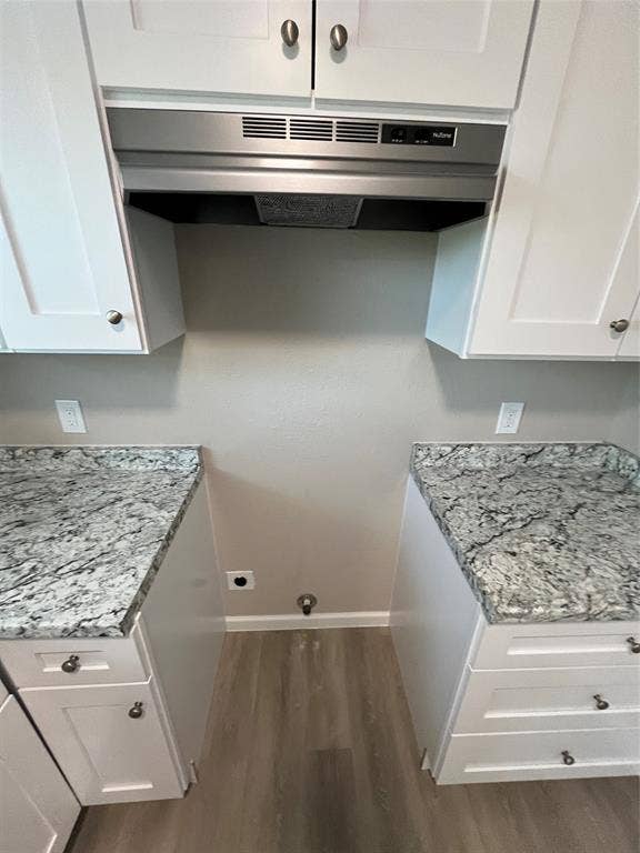 9527 Musgrave Drive, Dallas, TX 75217 White shaker-style cabinetry, stone-patterned countertops, stainless steel range hood, and wood-finish flooring