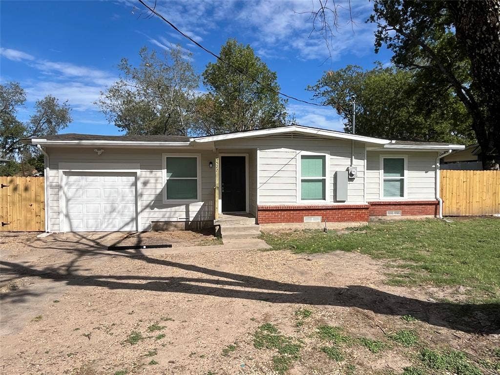 9527 Musgrave Drive, Dallas, TX 75217 Single-story exterior featuring light-toned horizontal siding, a red brick base, an attached garage, and wood-panel perimeter fencing