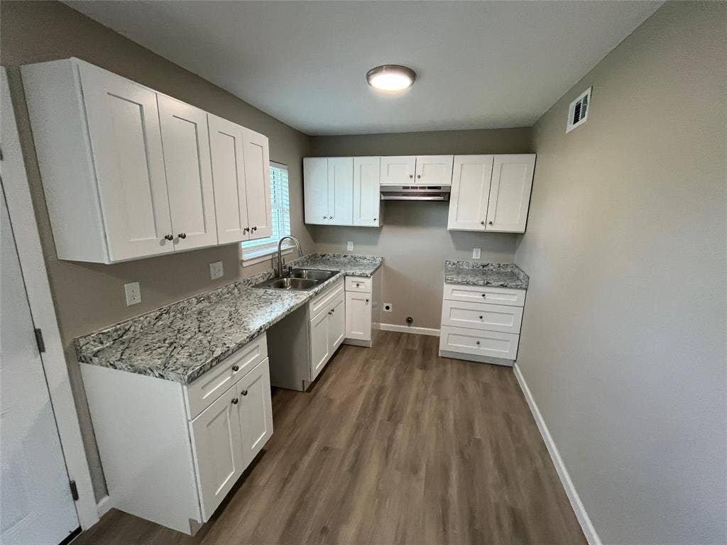 9527 Musgrave Drive, Dallas, TX 75217 Kitchen featuring white cabinetry, stone-patterned countertops, wood-finish flooring, stainless steel sink with a goose-neck faucet, and a range hood