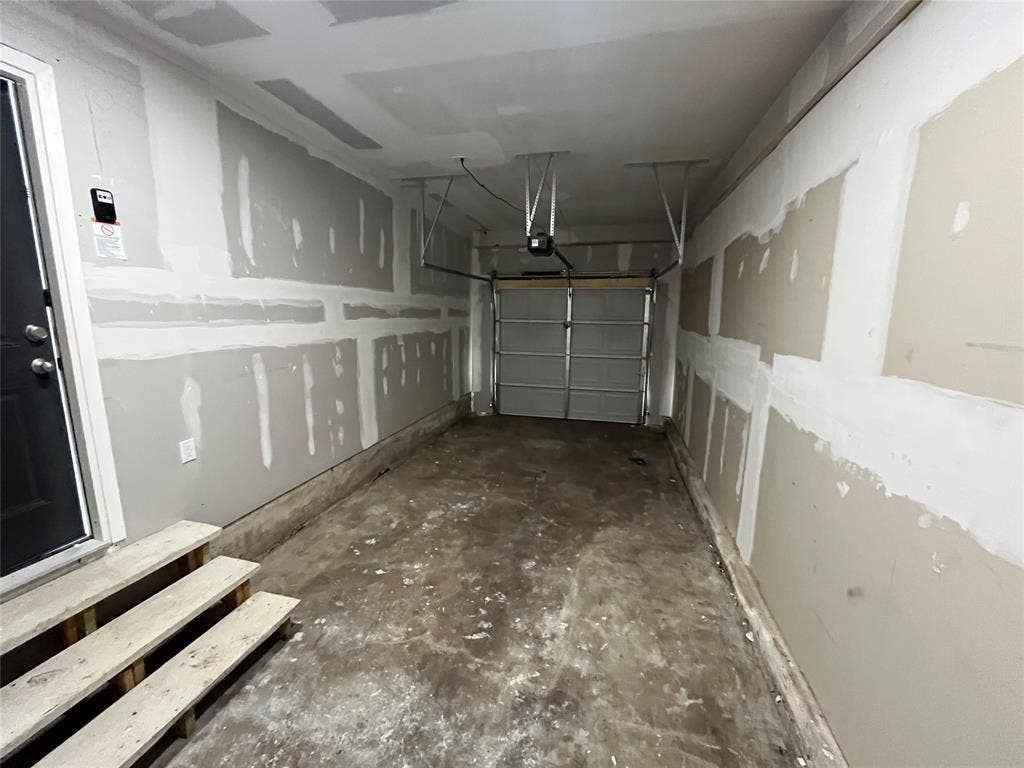9527 Musgrave Drive, Dallas, TX 75217 Single-vehicle garage featuring unfinished drywall, a concrete floor, an automated overhead door system, and wooden interior access steps