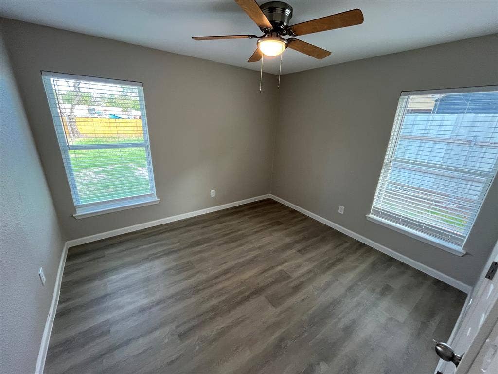 9527 Musgrave Drive, Dallas, TX 75217 Neutral-toned interior featuring wood-finish flooring, dual windows with blinds, and a centrally mounted ceiling fan