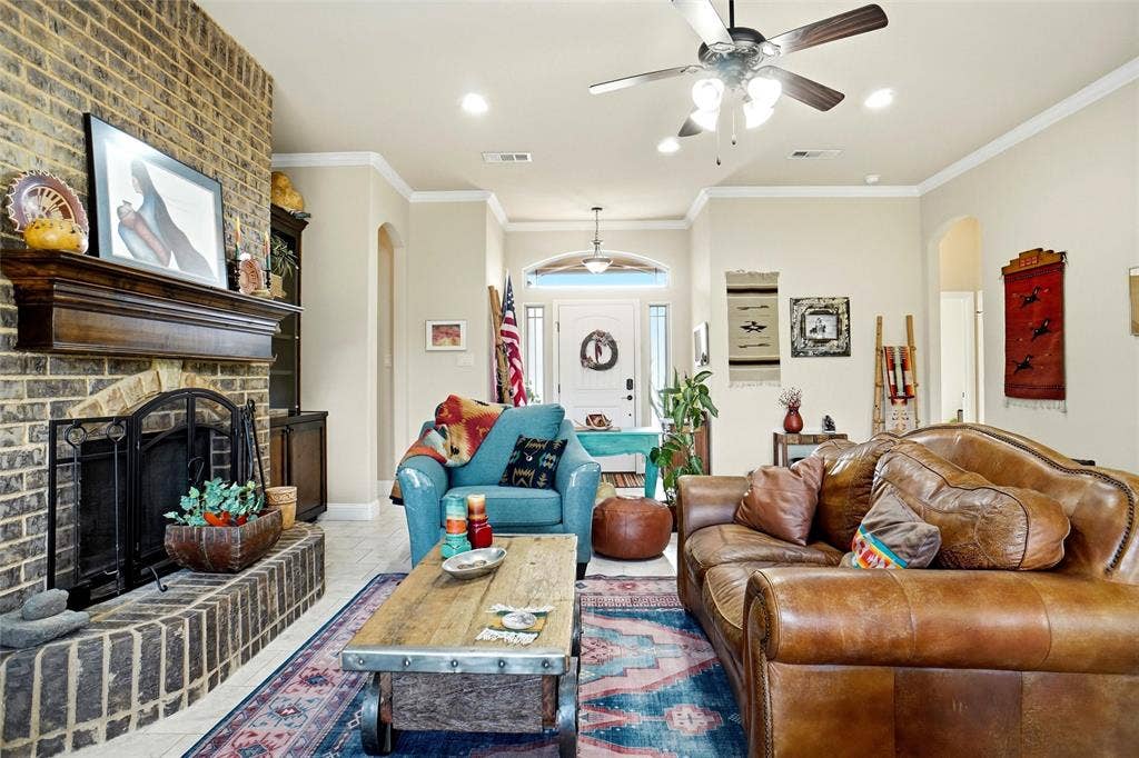 Brick fireplace with a wood mantel, recessed lighting, ceiling fan, and arched entryways