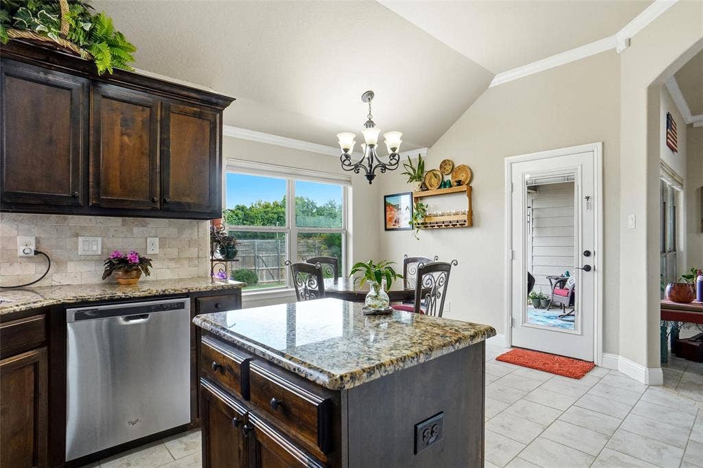 Kitchen featuring dark wood cabinetry, stone countertops, a central island, stainless steel dishwasher, and tiled flooring