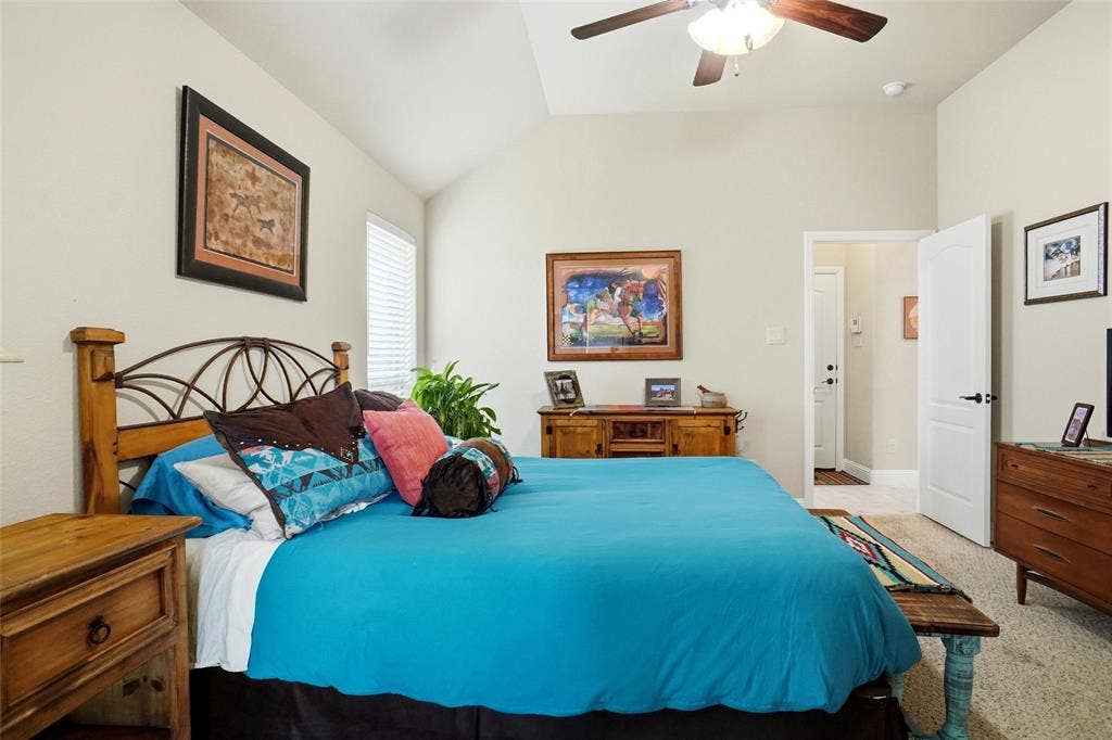 Vaulted ceiling featuring a central lighted ceiling fan, neutral wall tones, wall-to-wall carpeting, and multi-panel interior doors
