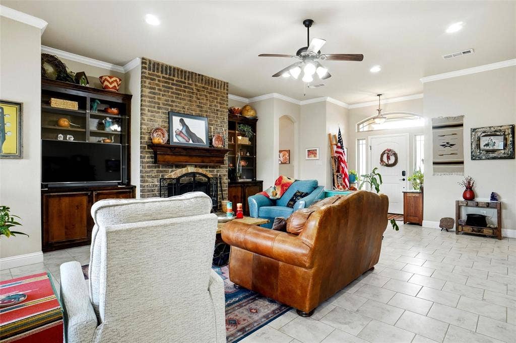 Living area featuring a floor-to-ceiling brick fireplace with a custom wood mantel, built-in shelving, tile flooring, recessed lighting, and a transom window above the entryway