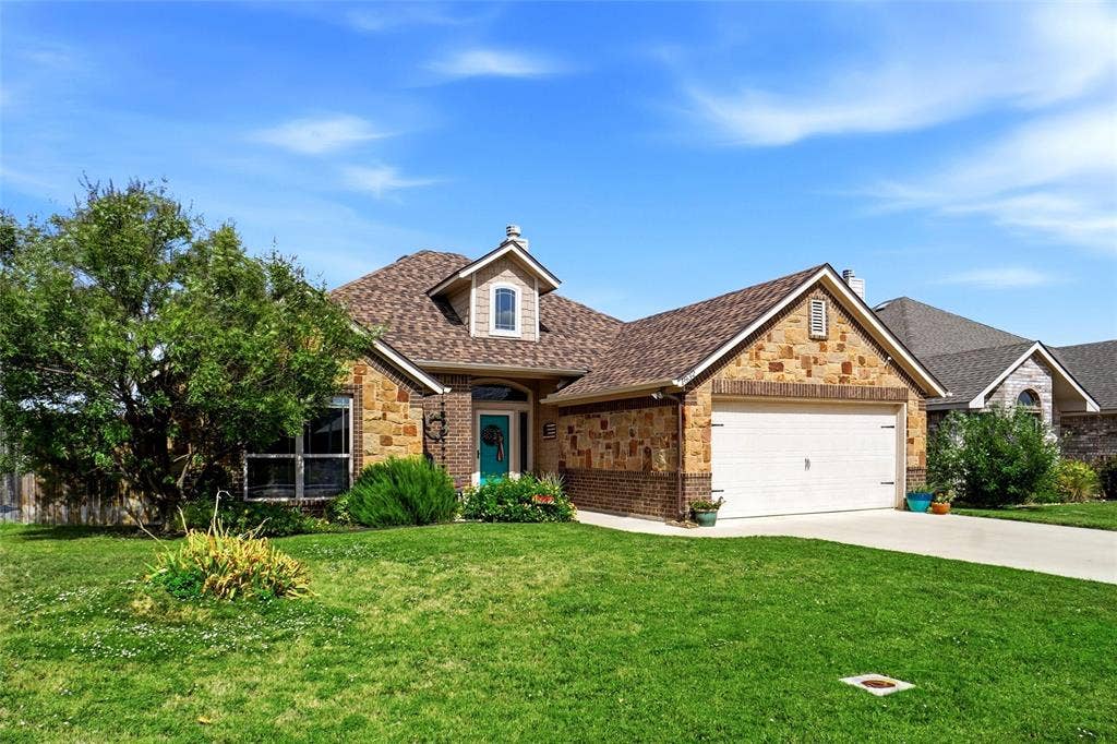 Exterior facade featuring a combination of stone and brick masonry, a multi-gabled roofline, a dormer window, and an attached two-car garage