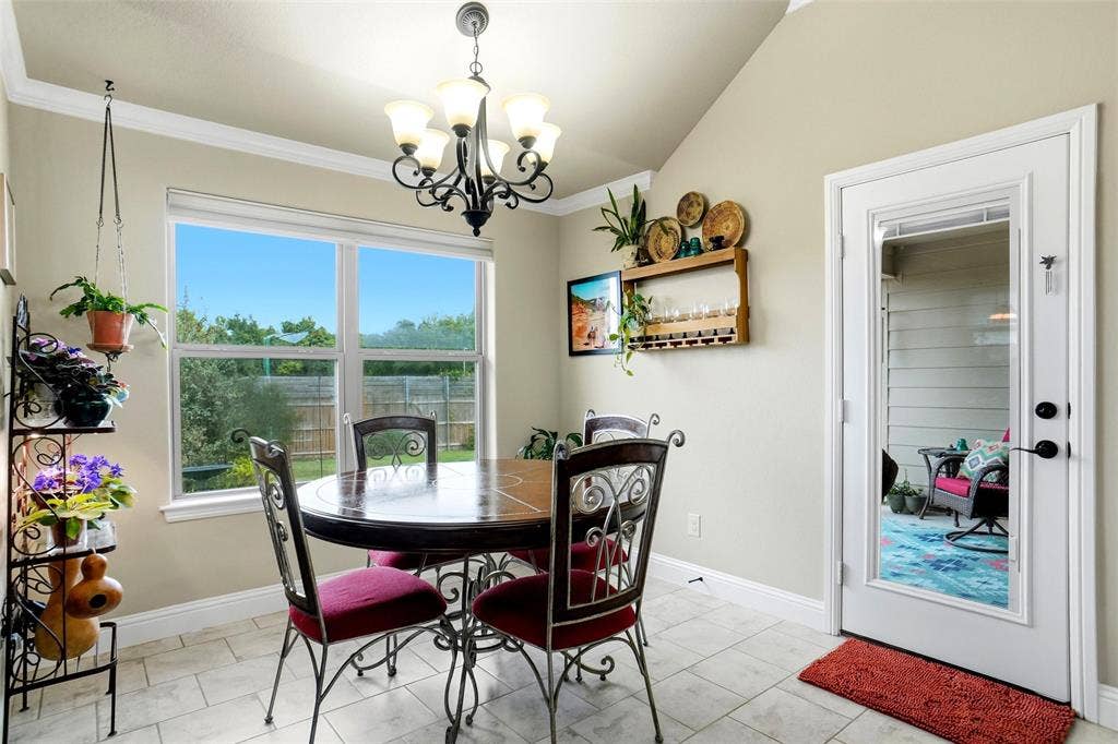Vaulted ceiling featuring a central multi-light chandelier, large picture window, and exterior door with a glass pane