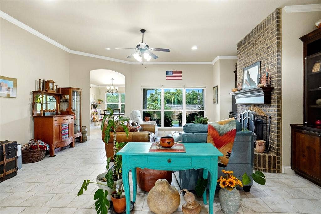 Living area featuring neutral tile flooring, a floor-to-ceiling brick fireplace with a custom mantle, built-in cabinetry, and large windows