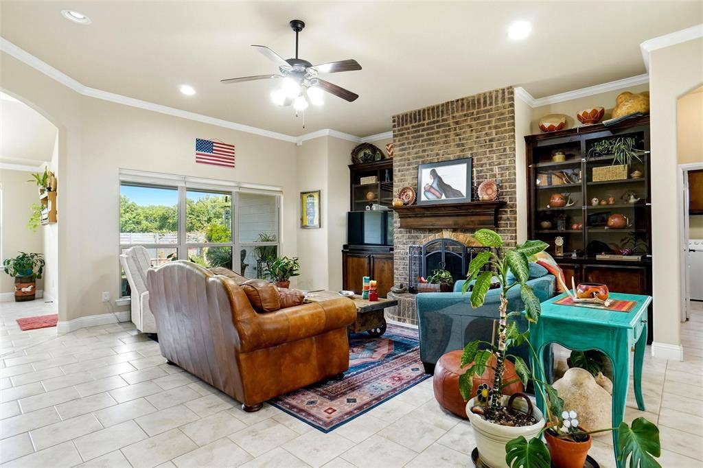 Living area featuring a floor-to-ceiling brick fireplace with a custom wood mantel, built-in cabinetry, recessed lighting, tile flooring, and large windows